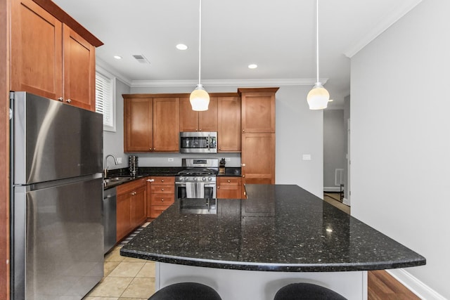 3938 N Southport Ave Unit G, Chicago, IL 60613 - kitchen with stainless steel appliances, crown molding, brown cabinetry, a kitchen island, and pendant lighting