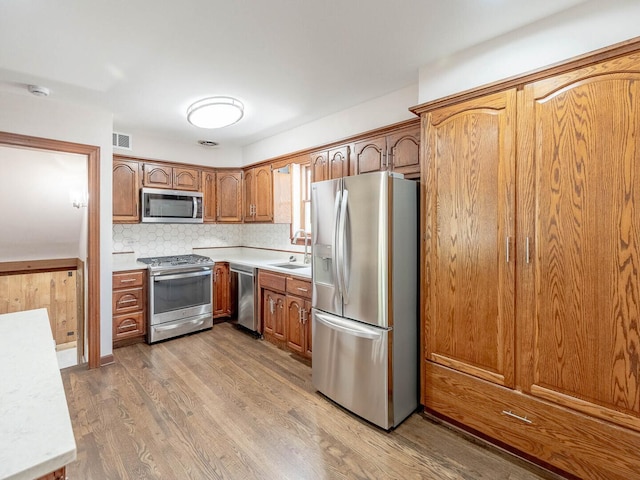 321 E Morningside Ave, Lombard, IL 60148 - kitchen featuring appliances with stainless steel finishes, light wood-style flooring, light countertops, brown cabinets, and decorative backsplash