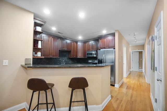 453 N May St Unit Gs, Chicago, IL 60642 - kitchen featuring stainless steel appliances, open shelves, a breakfast bar area, light wood-type flooring, and tasteful backsplash