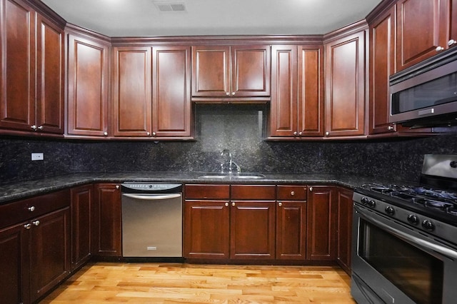 453 N May St Unit Gs, Chicago, IL 60642 - kitchen featuring appliances with stainless steel finishes, light wood-type flooring, decorative backsplash, and reddish brown cabinets