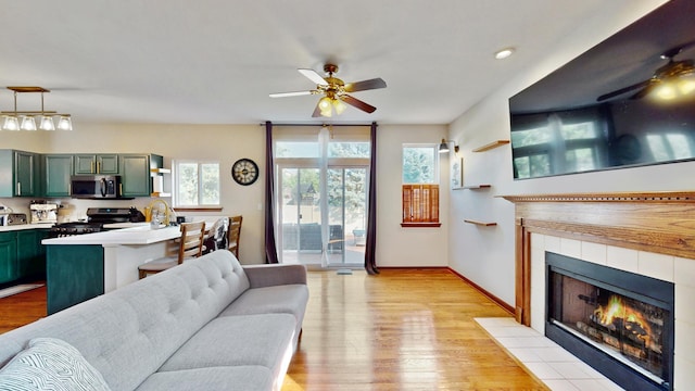 1389 Lily Cache Ln, Bolingbrook, IL 60490 - living room featuring ceiling fan, a tile fireplace, and light wood-type flooring