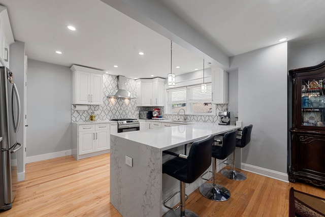 8313 W Ballard Rd, Niles, IL 60714 - kitchen featuring wall chimney range hood, stainless steel appliances, decorative backsplash, a kitchen breakfast bar, and light wood-type flooring