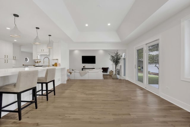 19635 Swanberg Ln, Mokena, IL 60448 - kitchen featuring white cabinetry, light wood-style flooring, a kitchen breakfast bar, light countertops, and pendant lighting