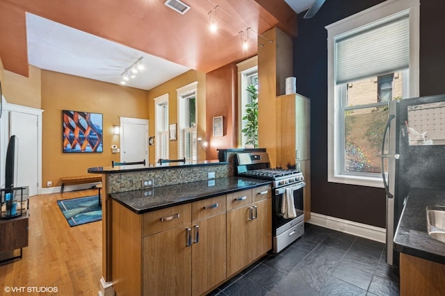 909 W Wisconsin St Unit 1M, Chicago, IL 60614 - kitchen with appliances with stainless steel finishes, track lighting, a peninsula, brown cabinetry, and dark stone countertops