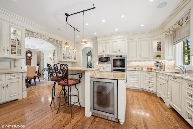 85 Ela Rd, Inverness, IL 60067 - kitchen with wine cooler, arched walkways, stainless steel appliances, light wood-style floors, and a kitchen island