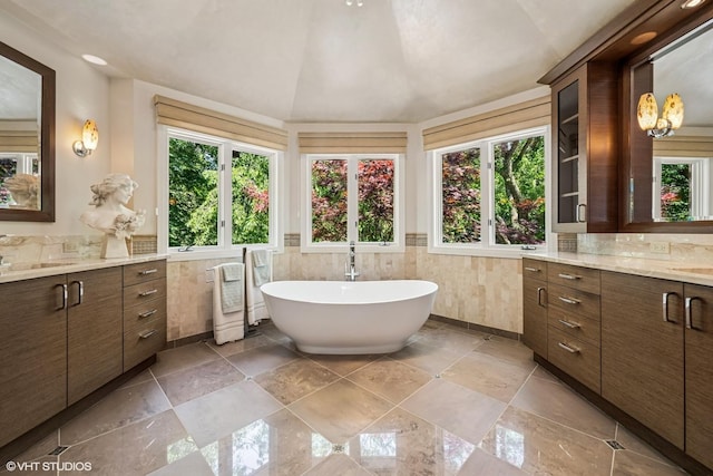 85 Ela Rd, Inverness, IL 60067 - full bathroom with vanity, a freestanding tub, a wainscoted wall, lofted ceiling, and tile walls