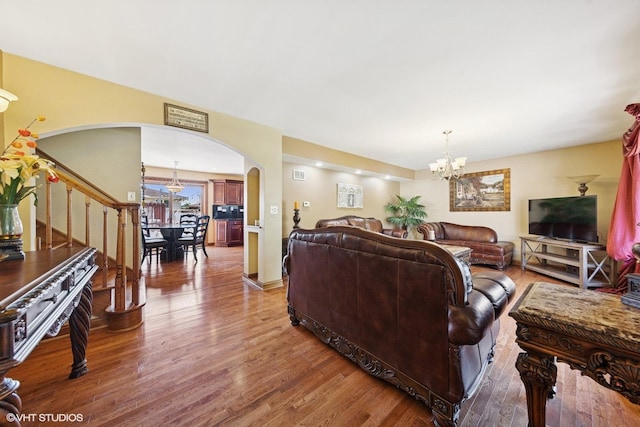 8437 167th St, Tinley Park, IL 60487 - living room featuring arched walkways, a chandelier, wood finished floors, and stairs