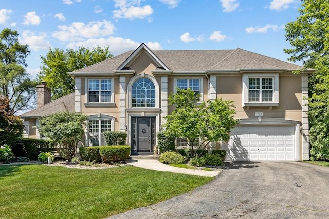 262 Hawk Hollow Dr, Bartlett, IL 60103 - colonial-style house with a garage, driveway, stucco siding, a front lawn, and a shingled roof
