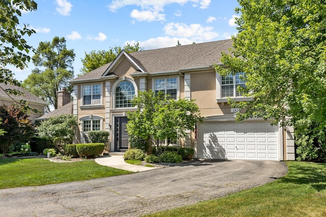 262 Hawk Hollow Dr, Bartlett, IL 60103 - view of front facade with an attached garage, driveway, stucco siding, a front yard, and roof with shingles