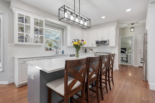 262 Hawk Hollow Dr, Bartlett, IL 60103 - kitchen featuring a kitchen breakfast bar, wood finished floors, stainless steel microwave, white cabinetry, and recessed lighting