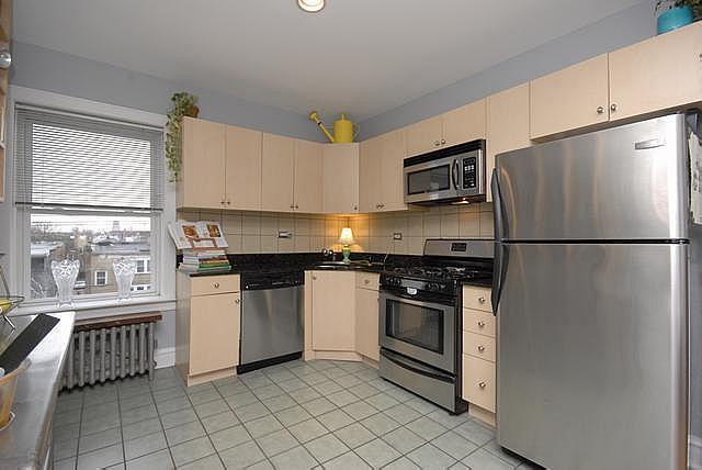 3135 W Leland Ave Unit 3W, Chicago, IL 60625 - kitchen featuring stainless steel appliances, cream cabinetry, light tile patterned flooring, radiator, and decorative backsplash