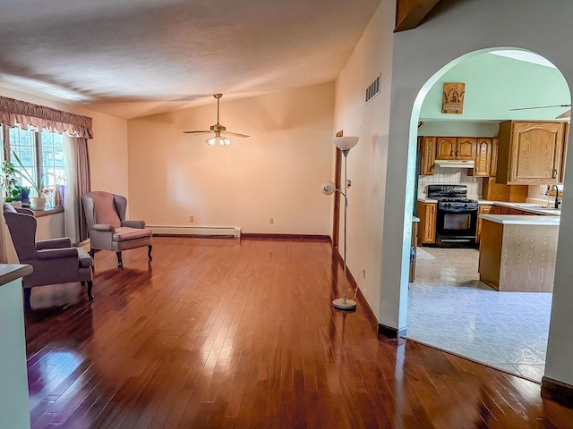 202 E 8th St, Gridley, IL 61744 - living area featuring hardwood / wood-style floors, a baseboard heating unit, ceiling fan, and arched walkways