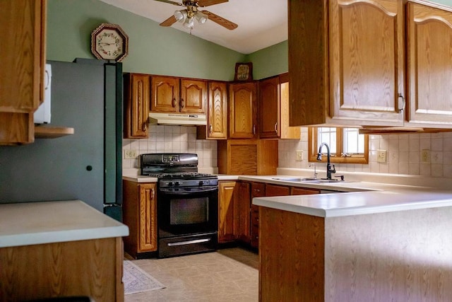 202 E 8th St, Gridley, IL 61744 - kitchen with black gas stove, under cabinet range hood, brown cabinets, light countertops, and vaulted ceiling
