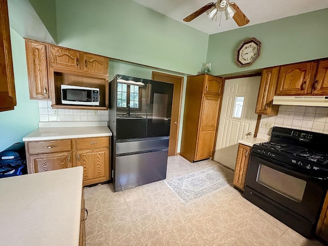 202 E 8th St, Gridley, IL 61744 - kitchen with black range with gas stovetop, freestanding refrigerator, stainless steel microwave, under cabinet range hood, and a ceiling fan