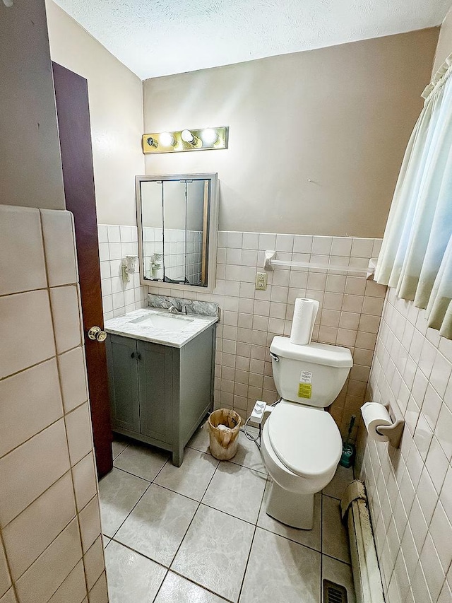 202 E 8th St, Gridley, IL 61744 - bathroom with tile walls, vanity, tile patterned flooring, a baseboard heating unit, and a wainscoted wall
