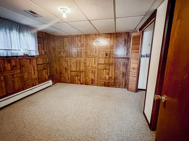 202 E 8th St, Gridley, IL 61744 - unfurnished room featuring wooden walls, a drop ceiling, carpet flooring, and baseboard heating