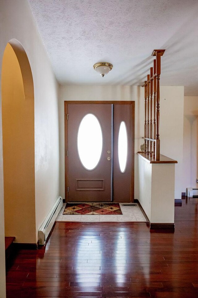 202 E 8th St, Gridley, IL 61744 - foyer entrance featuring a baseboard radiator, hardwood / wood-style flooring, arched walkways, and a textured ceiling