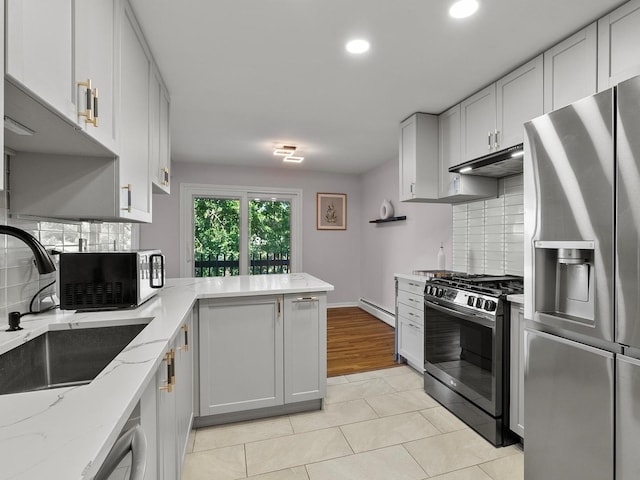 940 E Old Willow Rd Unit 305, Prospect Heights, IL 60070 - kitchen featuring appliances with stainless steel finishes, a baseboard radiator, under cabinet range hood, light tile patterned flooring, and tasteful backsplash