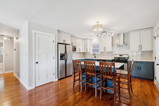 105 E Vermont St, Villa Park, IL 60181 - kitchen with stainless steel appliances, wall chimney exhaust hood, decorative backsplash, wood finished floors, and light countertops