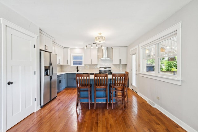 105 E Vermont St, Villa Park, IL 60181 - kitchen with appliances with stainless steel finishes, wall chimney range hood, light countertops, backsplash, and white cabinets