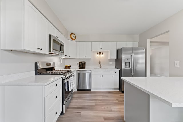 6S184 Lakewood Dr, Naperville, IL 60540 - kitchen featuring appliances with stainless steel finishes, light wood-style floors, white cabinetry, and light stone countertops