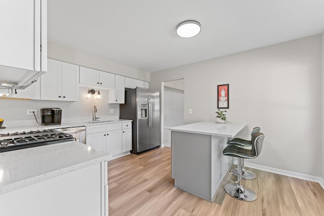6S184 Lakewood Dr, Naperville, IL 60540 - kitchen with stainless steel appliances, a peninsula, white cabinetry, a kitchen breakfast bar, and light wood finished floors