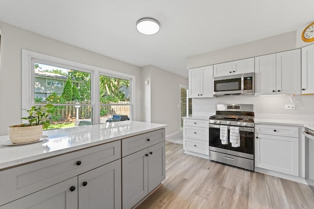 6S184 Lakewood Dr, Naperville, IL 60540 - kitchen featuring stainless steel appliances, light wood-type flooring, white cabinets, and light stone countertops