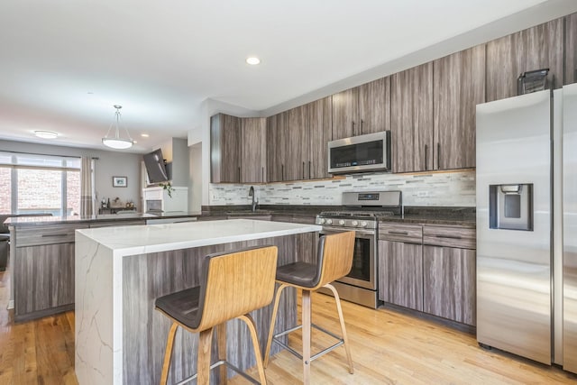 641 S Maple Ave Unit I, Oak Park, IL 60304 - kitchen with appliances with stainless steel finishes, backsplash, a center island, modern cabinets, and light wood-style floors