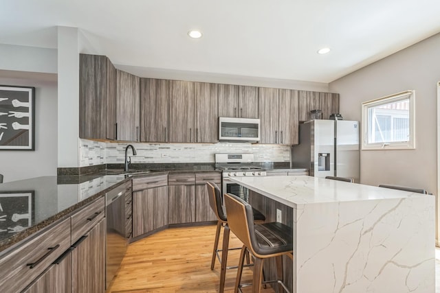 641 S Maple Ave Unit I, Oak Park, IL 60304 - kitchen with stainless steel appliances, light wood-style floors, a kitchen bar, decorative backsplash, and a center island