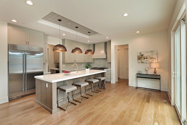 1947 Summerton Pl, Northbrook, IL 60062 - kitchen featuring appliances with stainless steel finishes, custom exhaust hood, a tray ceiling, decorative backsplash, and a breakfast bar area