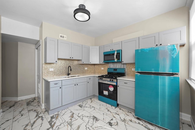 7548 S Harvard Ave, Chicago, IL 60620 - kitchen with refrigerator, gas stove, light countertops, gray cabinetry, and light marble finish flooring