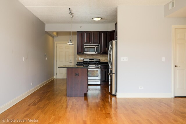 1670 Mill St Unit 508, Des Plaines, IL 60016 - kitchen with appliances with stainless steel finishes, a center island, decorative backsplash, and light wood finished floors