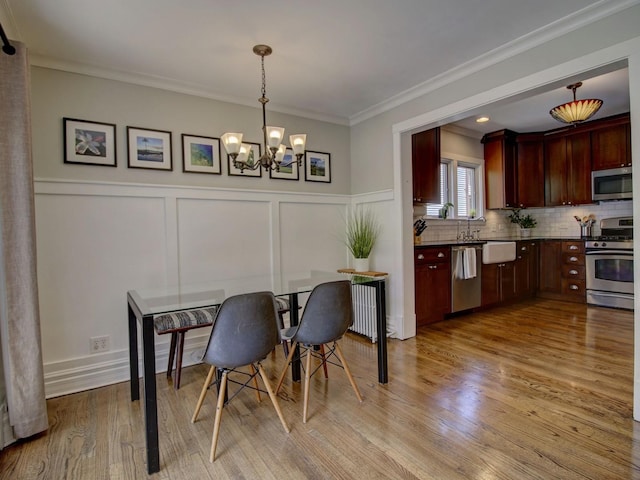415 N Taylor Ave, Oak Park, IL 60302 - dining space featuring a chandelier, light wood-style flooring, crown molding, a decorative wall, and wainscoting