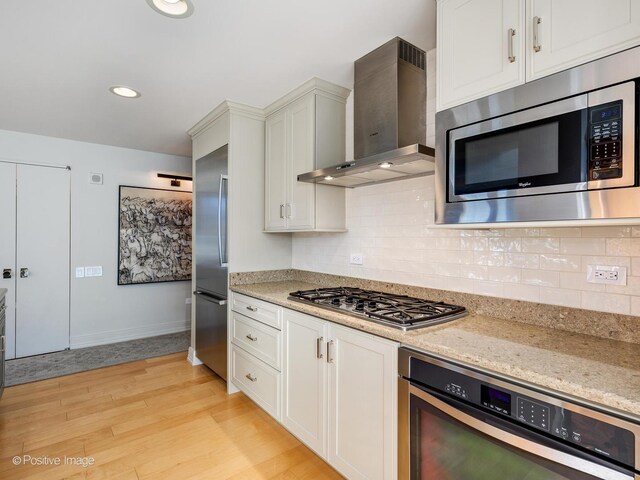 240 E Illinois St Unit 1002, Chicago, IL 60611 - kitchen featuring wall chimney range hood, stainless steel appliances, light wood-type flooring, backsplash, and light stone counters