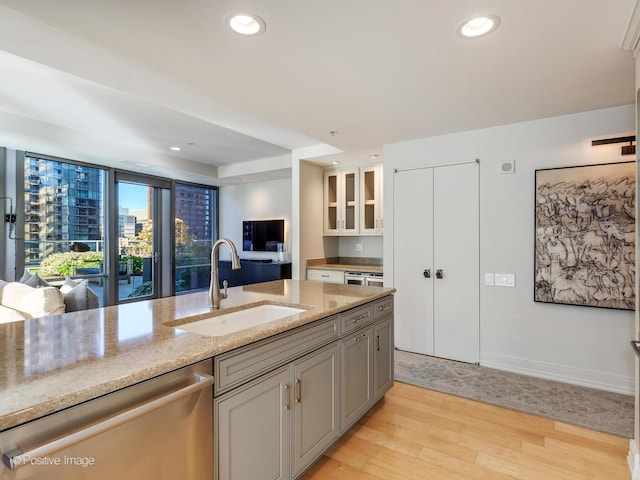 240 E Illinois St Unit 1002, Chicago, IL 60611 - kitchen featuring stainless steel dishwasher, light stone countertops, light wood-style flooring, glass insert cabinets, and recessed lighting