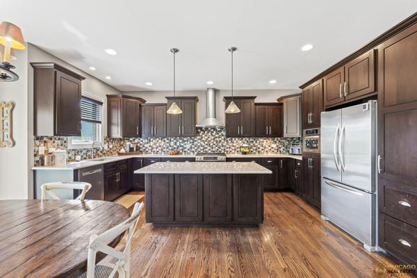 13119 Kinsale Ct, Lemont, IL 60439 - kitchen featuring stainless steel appliances, wall chimney exhaust hood, dark brown cabinets, a kitchen island, and recessed lighting
