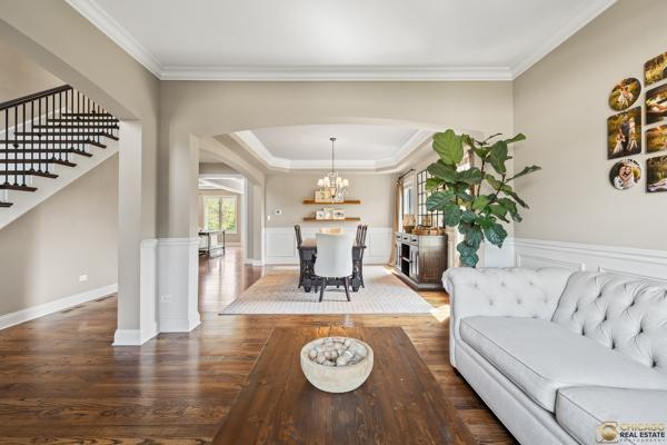 13119 Kinsale Ct, Lemont, IL 60439 - living room featuring stairway, arched walkways, wood finished floors, crown molding, and a chandelier