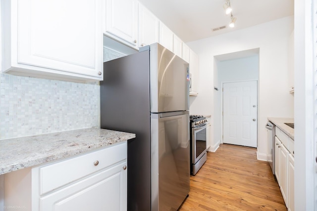 4536 N Sheridan Rd Unit 104, Chicago, IL 60640 - kitchen featuring appliances with stainless steel finishes, white cabinets, backsplash, light wood-style flooring, and light stone countertops