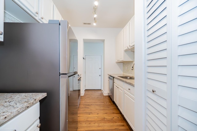 4536 N Sheridan Rd Unit 104, Chicago, IL 60640 - kitchen with stainless steel appliances, white cabinets, light wood-style flooring, backsplash, and light stone counters