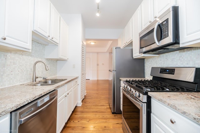 4536 N Sheridan Rd Unit 104, Chicago, IL 60640 - kitchen featuring appliances with stainless steel finishes, white cabinets, light wood-type flooring, tasteful backsplash, and light stone counters