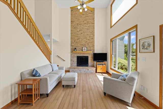 3220 Weeping Cherry Dr, Champaign, IL 61822 - living area featuring a high ceiling, wood finished floors, ceiling fan, a stone fireplace, and stairs