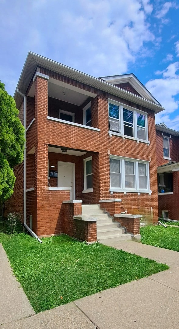 1623 S 58th Ct, Cicero, IL 60804 - view of front of home with a balcony, brick siding, and a front lawn