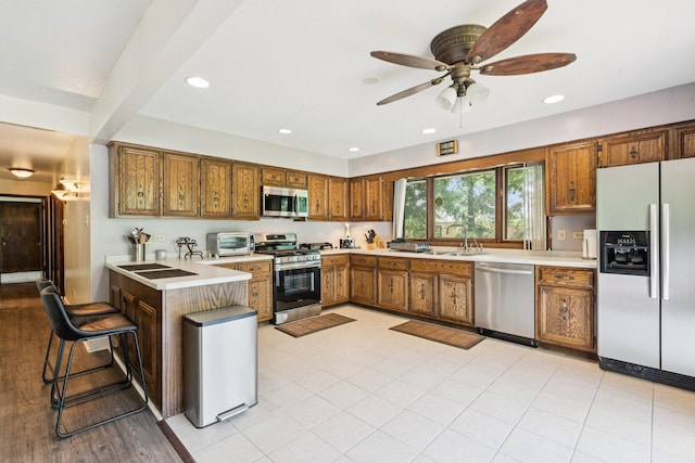 13115 Maple Rd, Mokena, IL 60448 - kitchen with stainless steel appliances, brown cabinets, light countertops, a peninsula, and ceiling fan