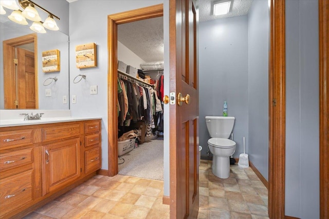 2903 Keystone Rd, Bloomington, IL 61704 - bathroom with a textured ceiling, vanity, and a walk in closet