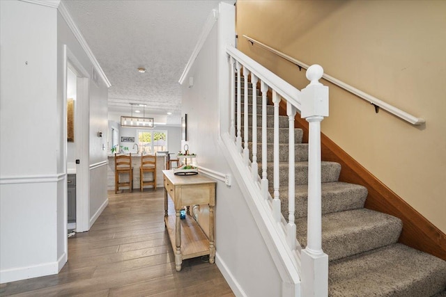 2903 Keystone Rd, Bloomington, IL 61704 - stairs featuring a textured ceiling, wood-type flooring, and ornamental molding