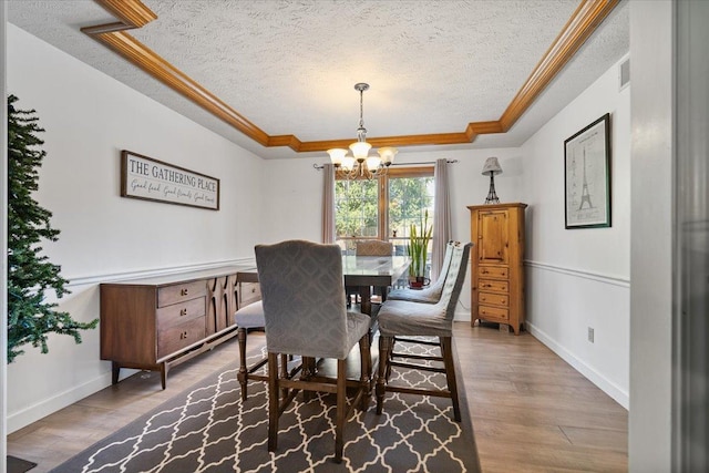 2903 Keystone Rd, Bloomington, IL 61704 - dining room featuring a textured ceiling, a tray ceiling, a chandelier, crown molding, and wood finished floors