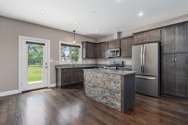 14903 S Preserve Dr, Lockport, IL 60441 - kitchen with appliances with stainless steel finishes, dark brown cabinets, light stone counters, a kitchen island, and dark wood-style flooring