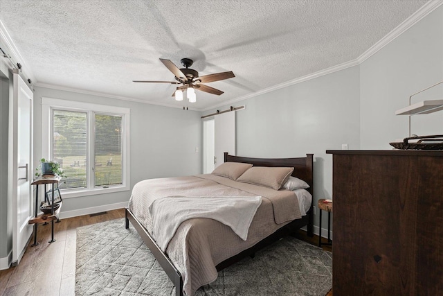 2911 E Oaks Rd N, Urbana, IL 61802 - bedroom with a barn door, wood finished floors, crown molding, a textured ceiling, and a ceiling fan