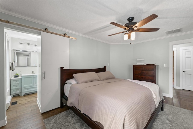 2911 E Oaks Rd N, Urbana, IL 61802 - bedroom with hardwood / wood-style flooring, ornamental molding, a barn door, a textured ceiling, and a ceiling fan