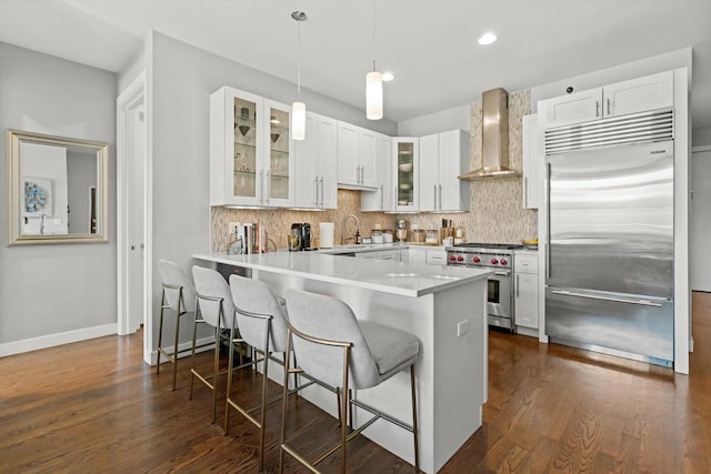 2140 W Armitage Ave Unit 3W, Chicago, IL 60647 - kitchen with premium appliances, wall chimney range hood, a kitchen breakfast bar, backsplash, and glass insert cabinets